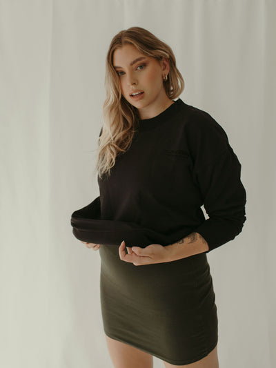 black crewneck sweatshirt layered with sage green knit dress