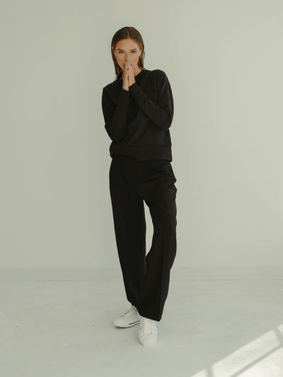 black minimal crewneck sweatshirt and pleated trouser monochrome outfit