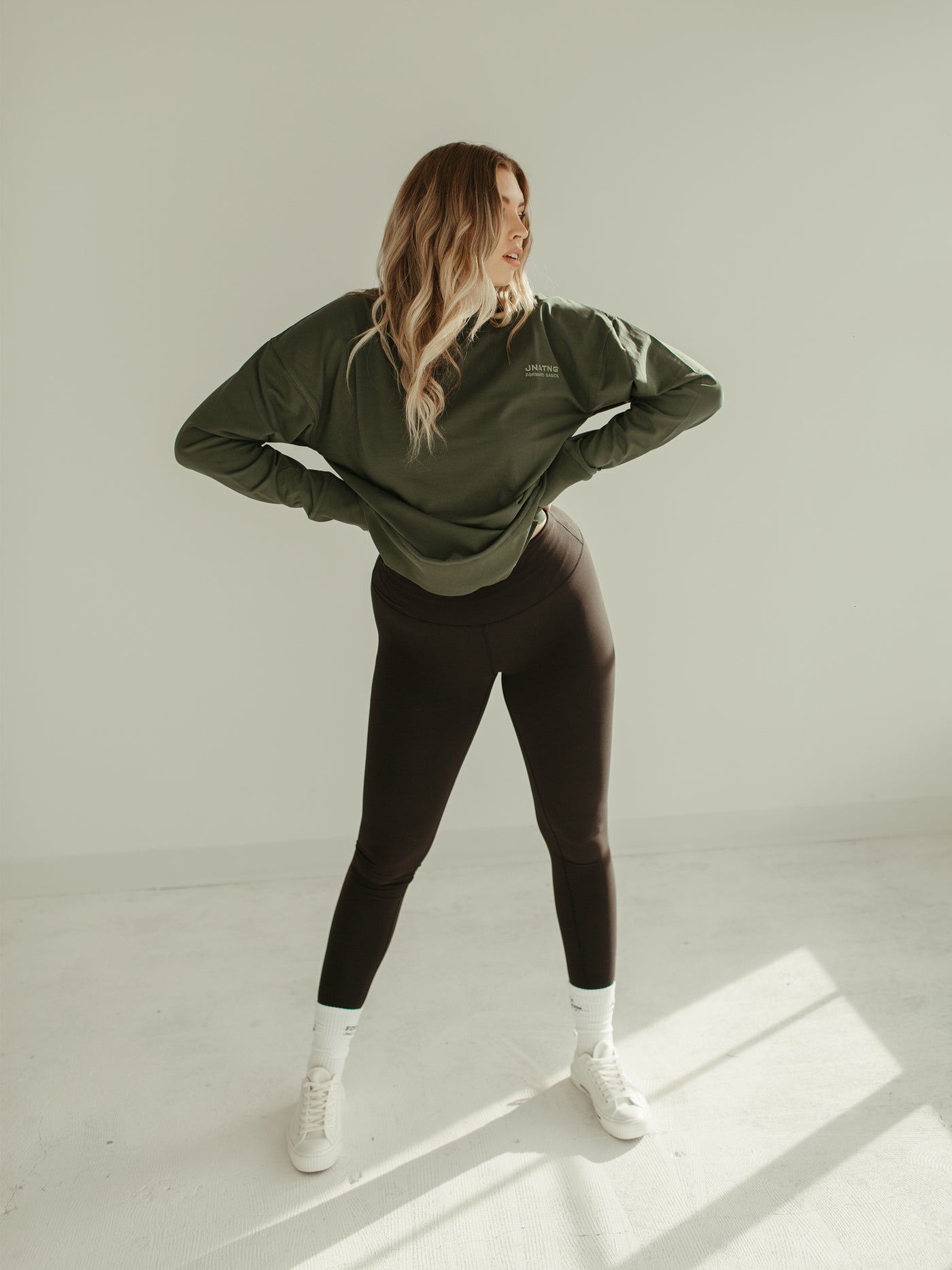 sage green crewneck sweatshirt with black leggings and converse