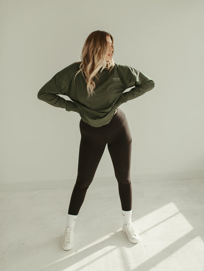 sage green crewneck sweatshirt with black leggings and converse