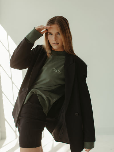 sage green crewneck sweatshirt with biker shorts and black blazer